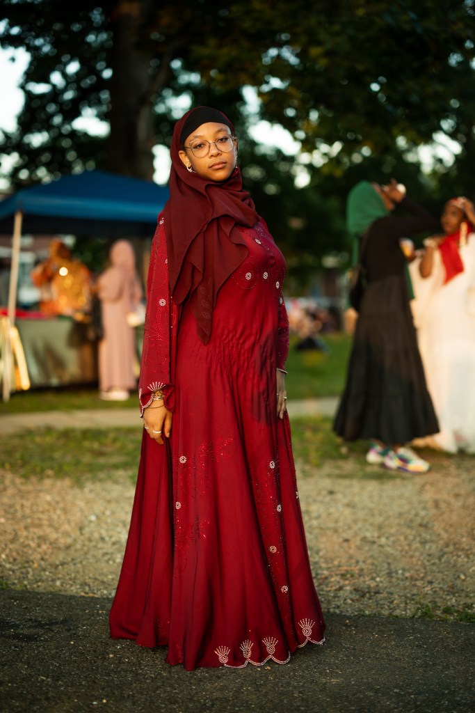 Outdoor portrait of a person wearing a long red outfit and glasses