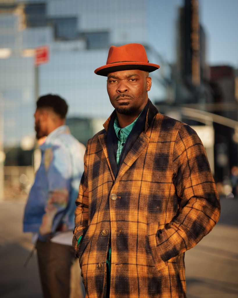 Portrait of a man in an orange hat and plaid coat on a city street