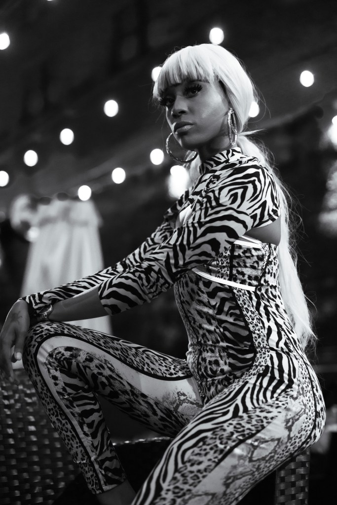 Black-and-white portrait of a woman in a patterned outfit beneath string lights