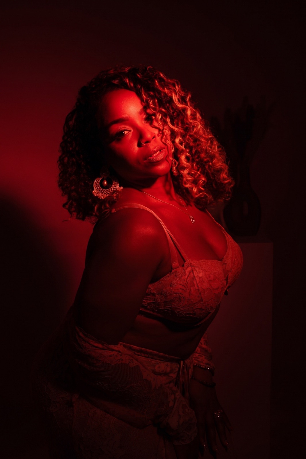Low-key red studio portrait with curls and a lace outfit
